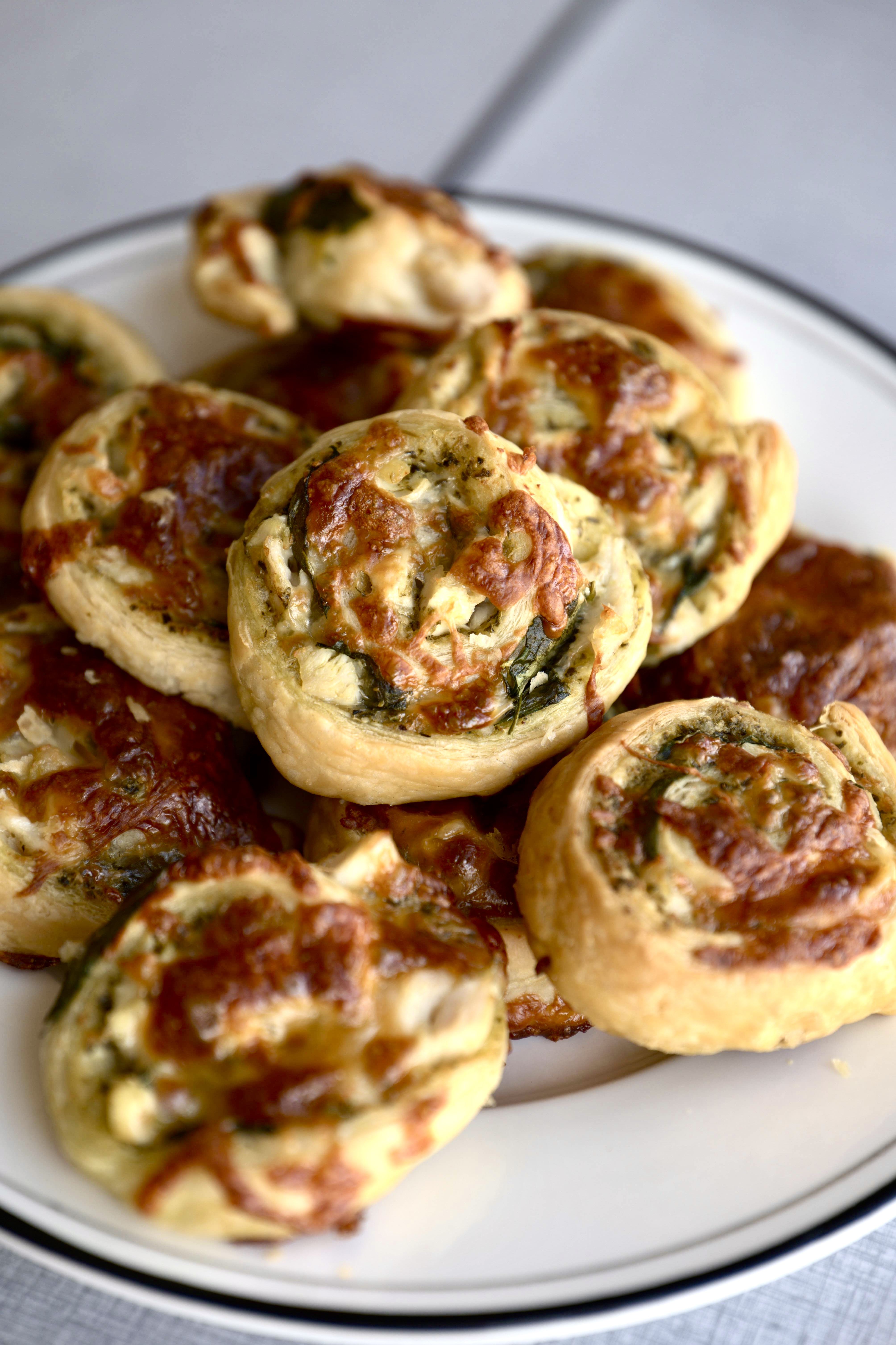 Butterdejssnegle med kylling, pesto, revet ost og spinat på en bageplade, klar til servering.
