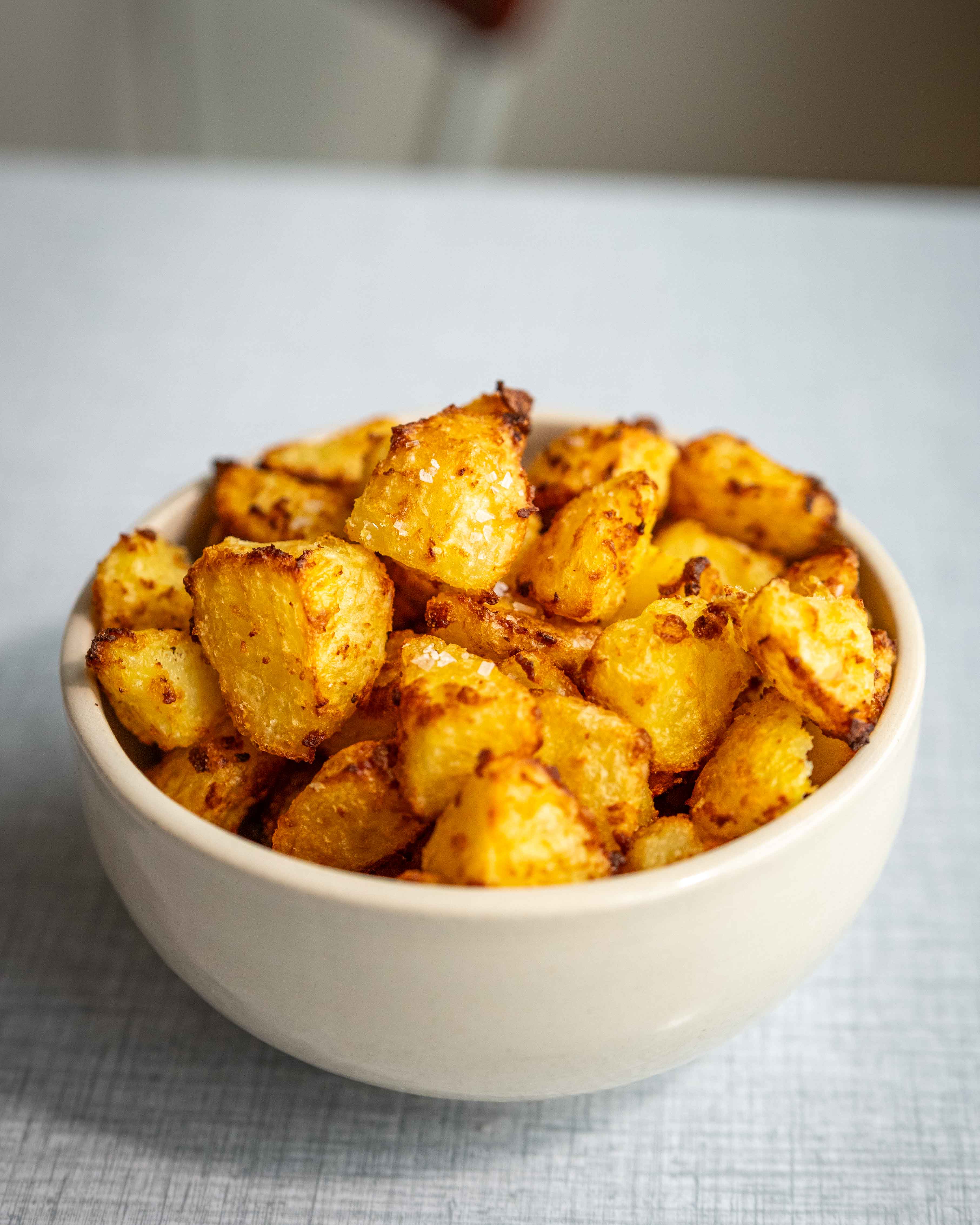 Sprøde airfryer-kartofler med gylden og knasende overflade serveret i en skål.