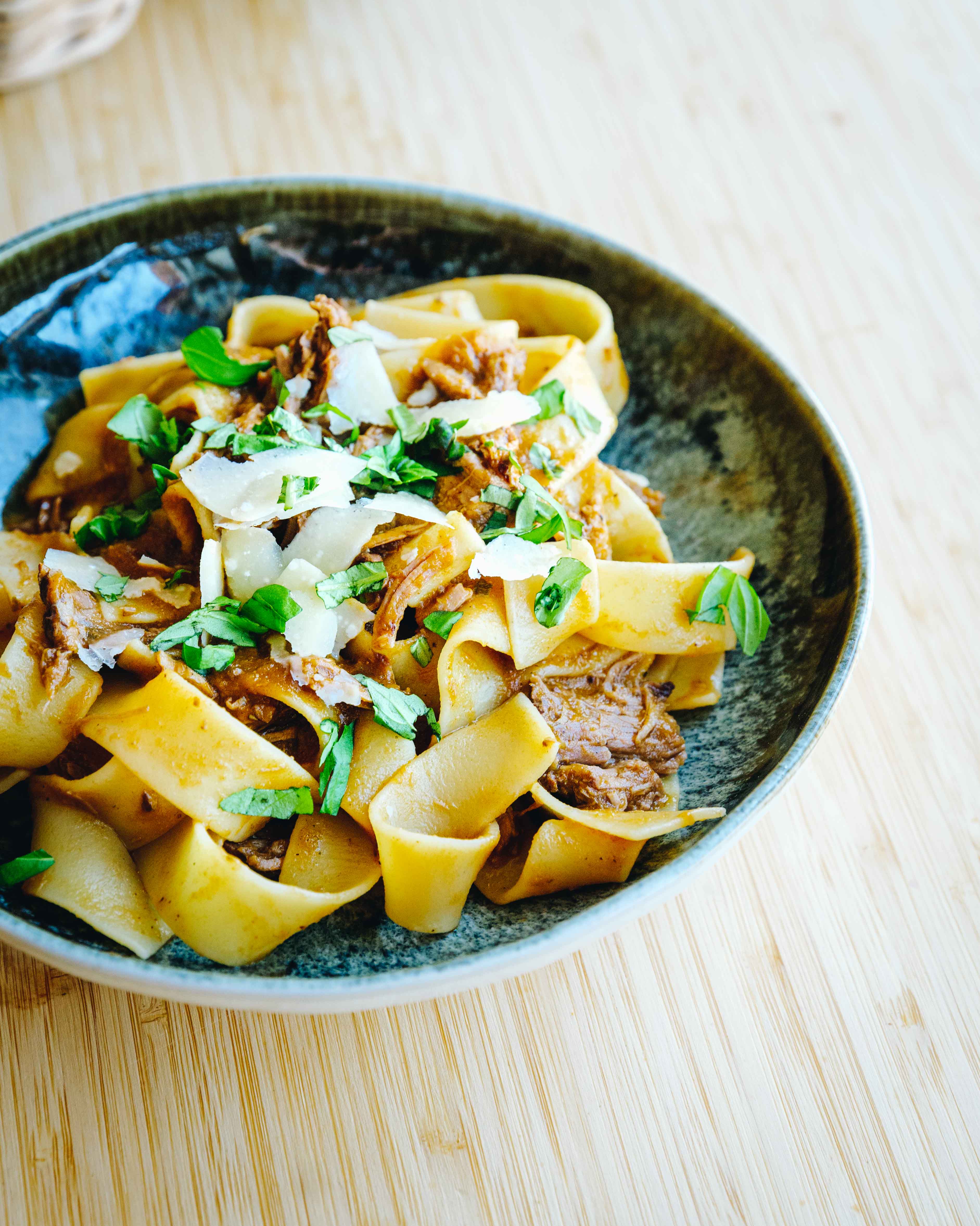 En tallerken med mør oksetykkam i rødvinsragú serveret med pasta og friskrevet parmesan.