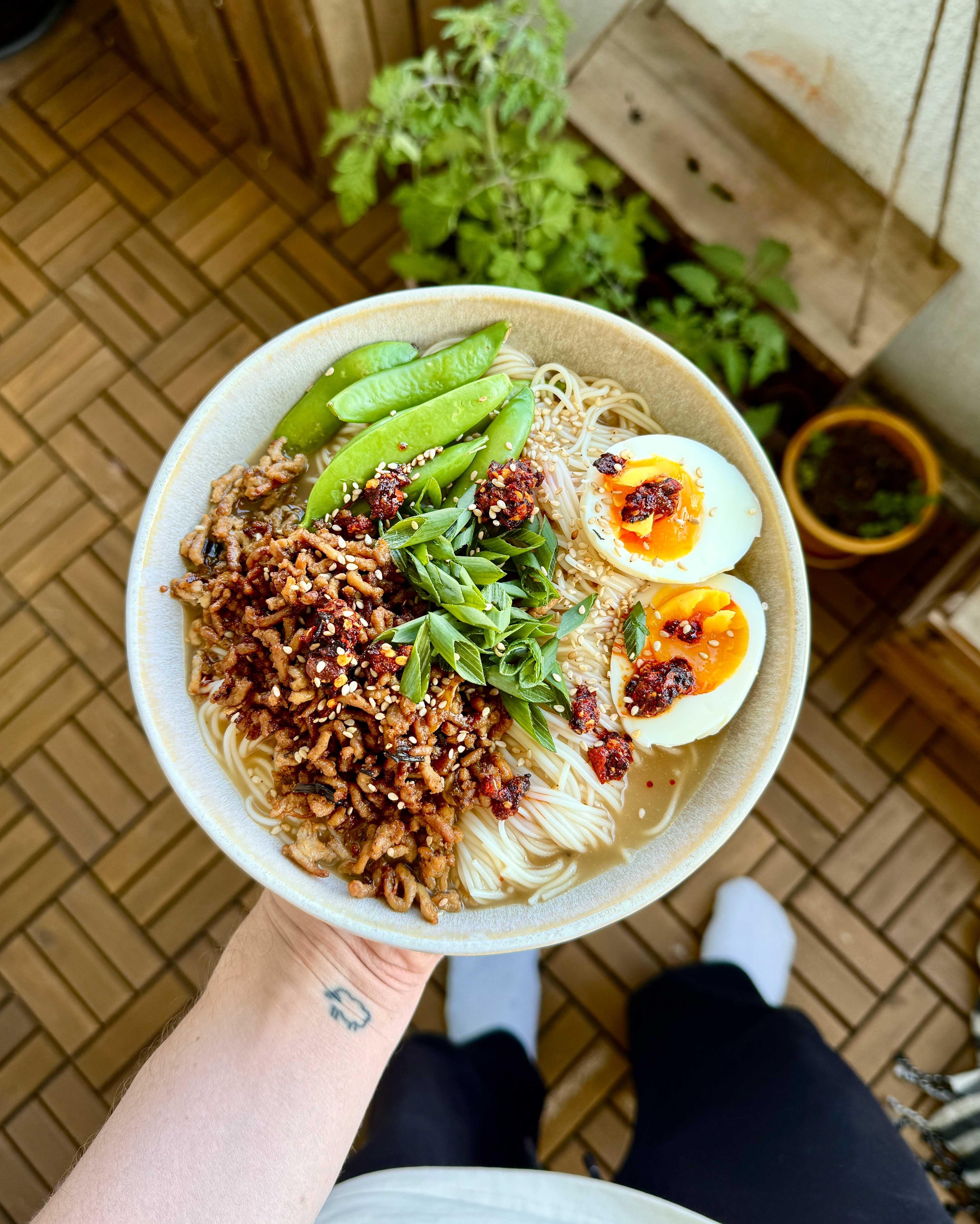 En skål hjemmelavet ramen med nudler, stegt svinekød, æg, sukkerærter og forårsløg.