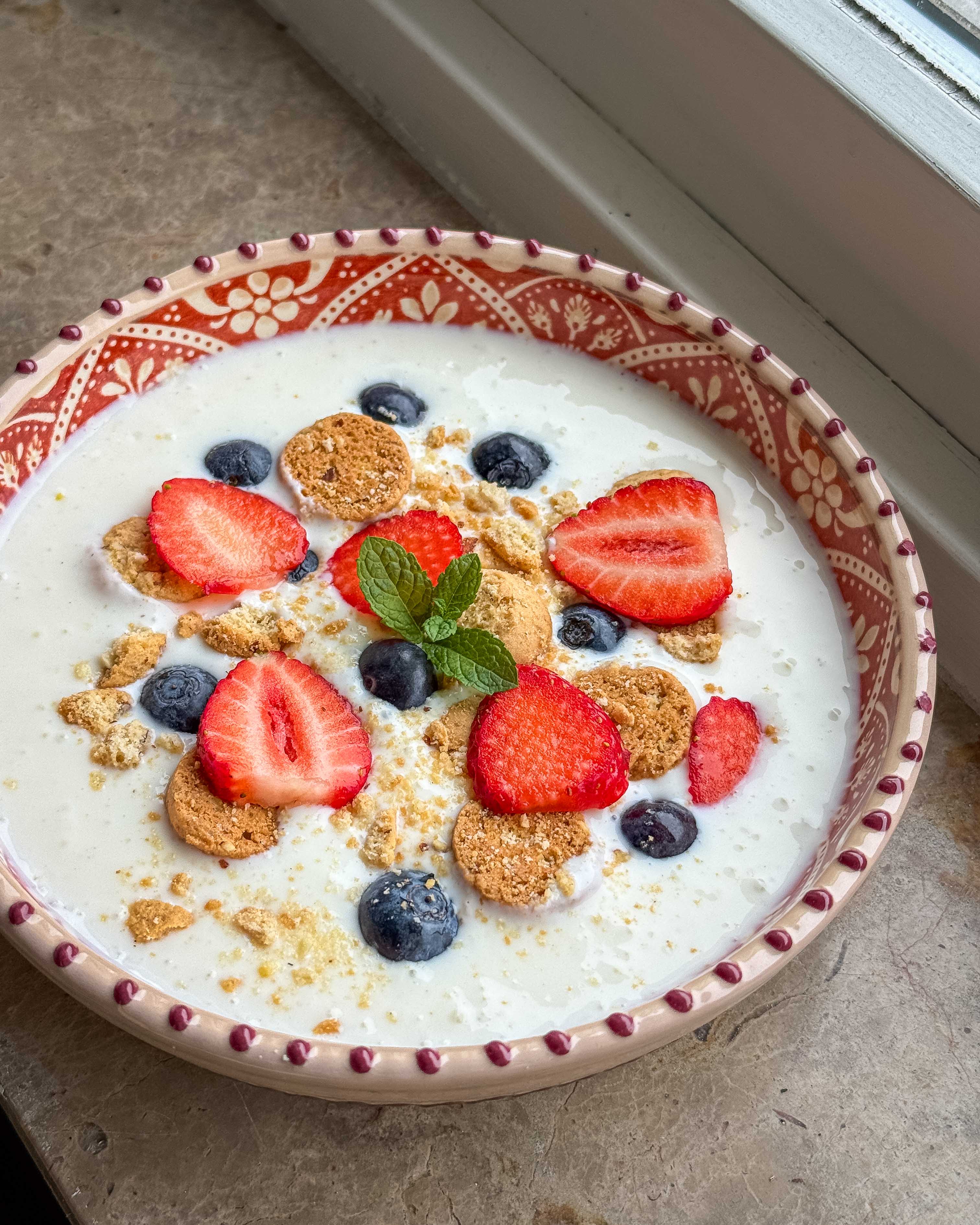 Skål med laktosefri koldskål toppet med kammerjunkere og friske bær på et sommerbord.