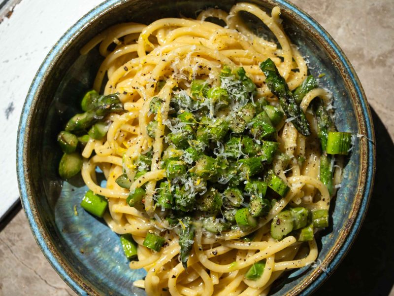 Cremet asparges carbonara med grønne asparges, pecorino, citron og sort peber serveret i en dyb tallerken.