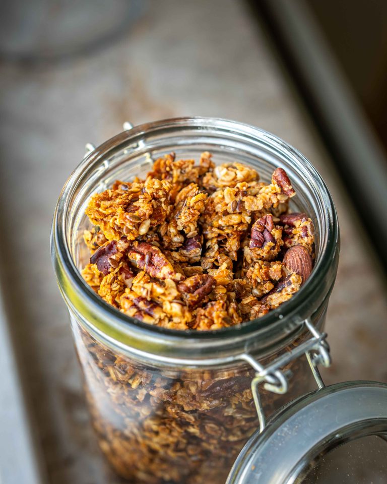 Hjemmelavet granola med havregryn, pekannødder, mandler og frø i et glas med tætsluttende låg.